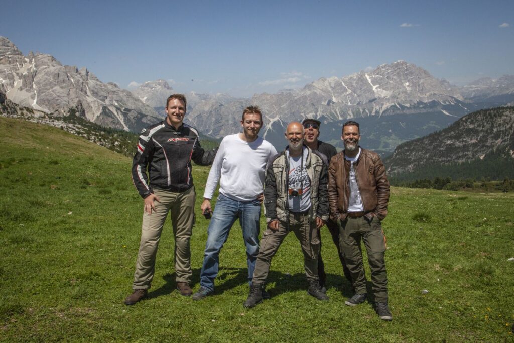 5 silly men mugging for the camera in front of a beautiful mountainous region.